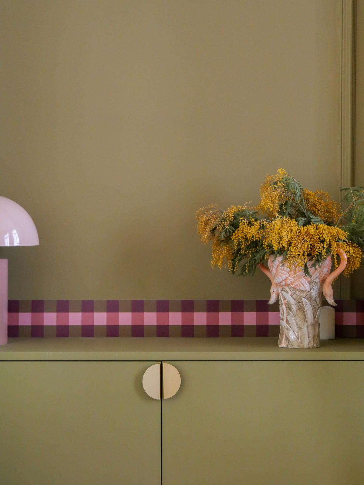Détail décor — frise Cadence Bordeaux et vase aux flamants roses garni de mimosa sur bahut vert olive Bilboquet Déco