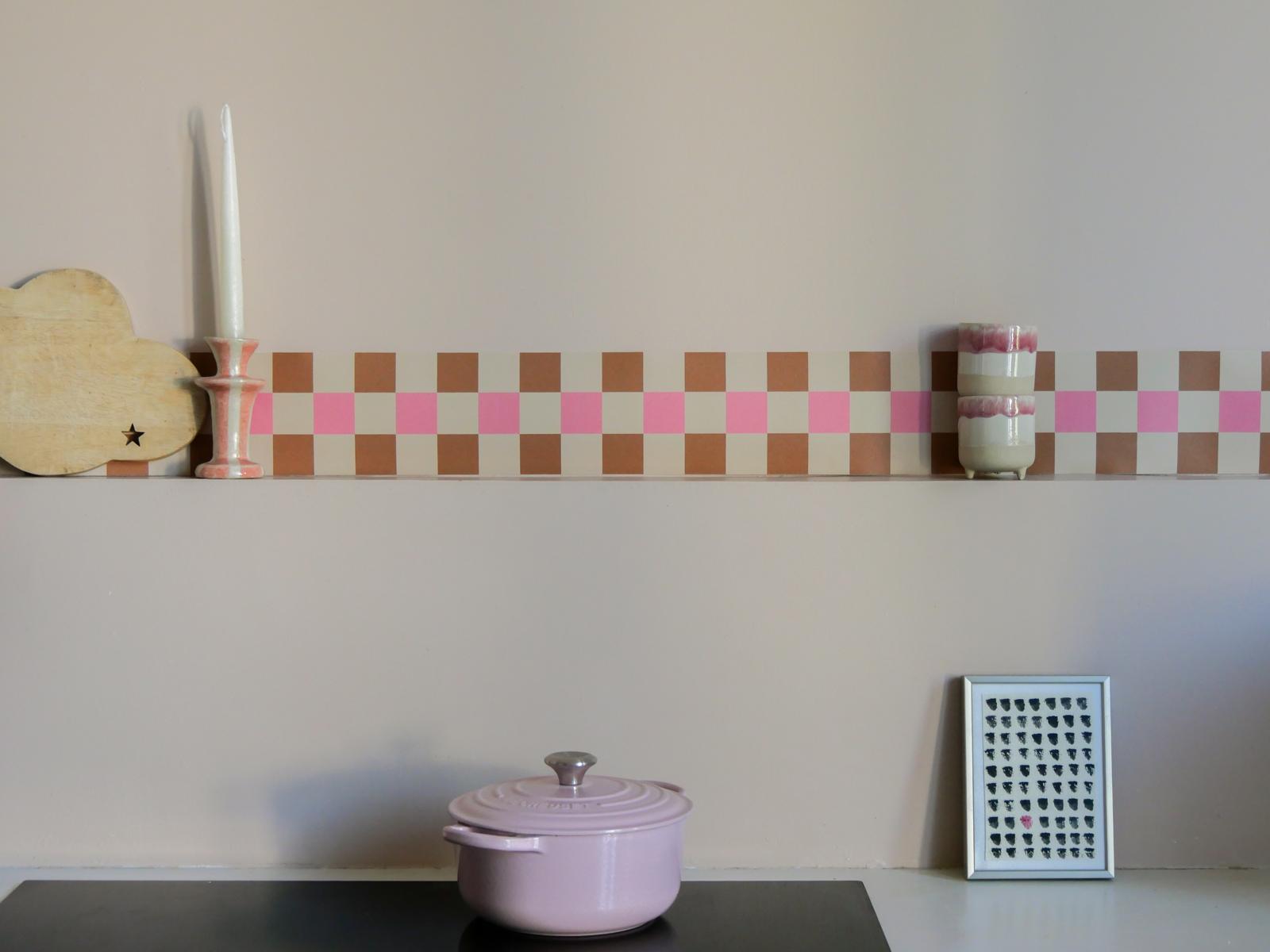 Frise Cadence Rose en damier camel, rose vif et crème posée en haut d'une étagère de cuisine — Bilboquet Déco