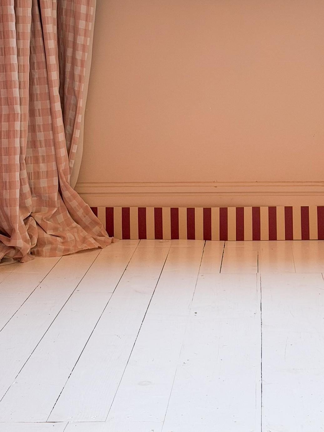 Frise Tempo Framboise installée en plinthe dans une pièce rose poudré, rayures framboise et crème — Bilboquet Déco