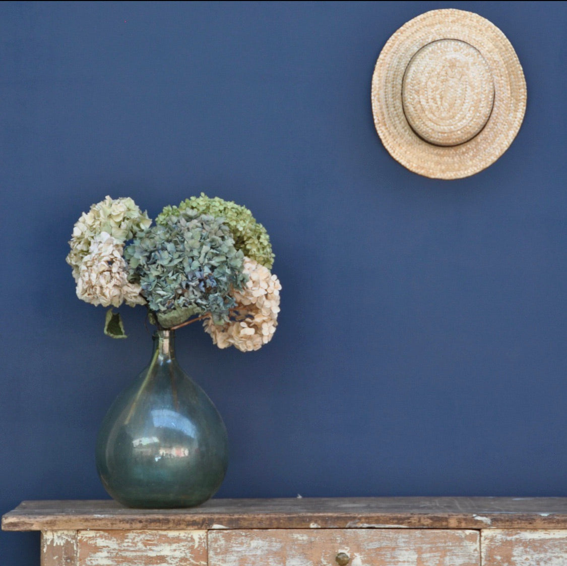 Intérieur aux murs Œil au beurre noir de Bilboquet Deco, bleu profond avec dame-jeanne et hortensias séchés