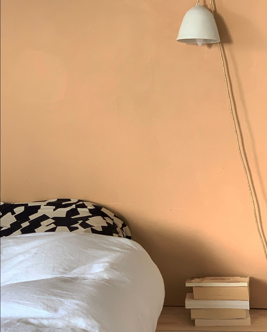 Chambre aux murs Tête brûlée de Bilboquet Deco, terracotta doux avec lampe et pile de livres
