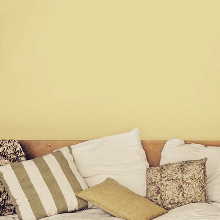 Chambre aux murs Puissance 4 de Bilboquet Deco, jaune paille avec tête de lit bois et coussins