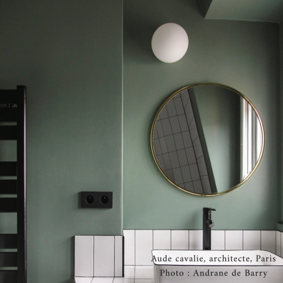 Salle de bain aux murs Camping sauvage de Bilboquet Deco, vert sauge avec miroir rond doré et carrelage blanc
