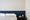 Papier peint Safari gris Bilboquet Déco posé en partie haute au-dessus d'un soubassement bleu profond dans une chambre d'adulte
