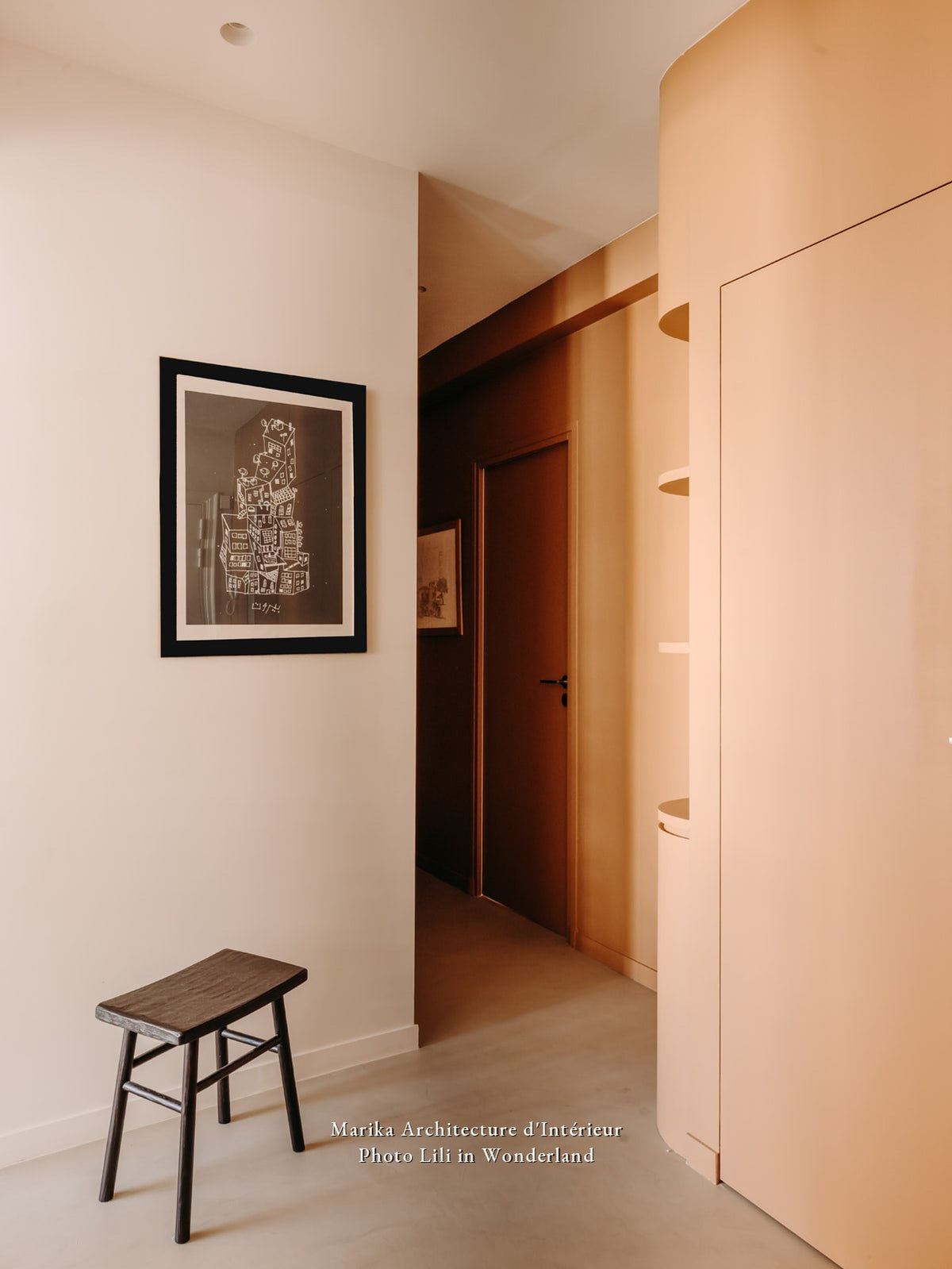 Couloir et placard arrondi peints en Beau Brun Bilboquet Déco, contraste avec un mur blanc et un tabouret noir