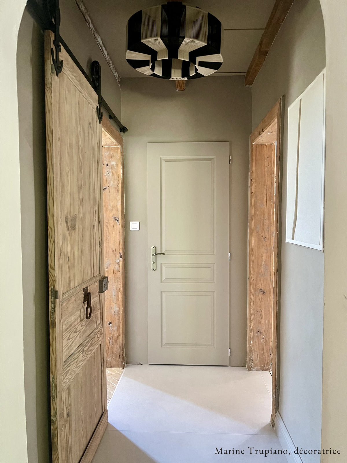 Couloir peint en Palio, peinture beige grisé Bilboquet Déco, porte en bois ancien et suspension en corde noir et blanc